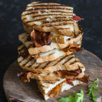 Stack grilled bacon sandwiches on wooden cutting board
