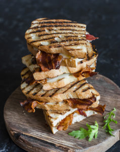Stack grilled bacon sandwiches on wooden cutting board