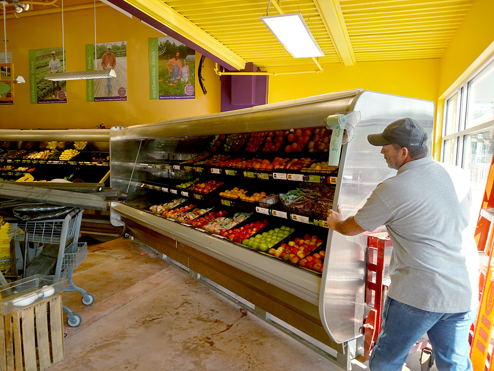 men moving produce cooler in store