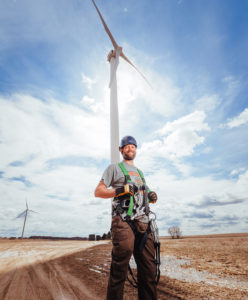 Man with gear in front of wind turbine