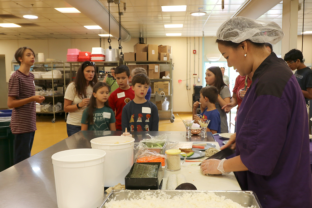 Su makes sushi while visitors watch