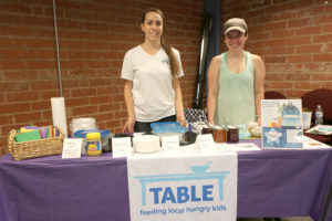 Two women pose behind the TABLE booth