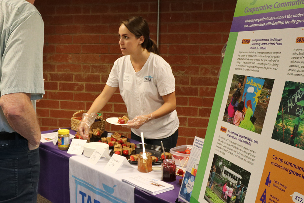 A woman serving skewers with small PB&J sandwiches and fruit