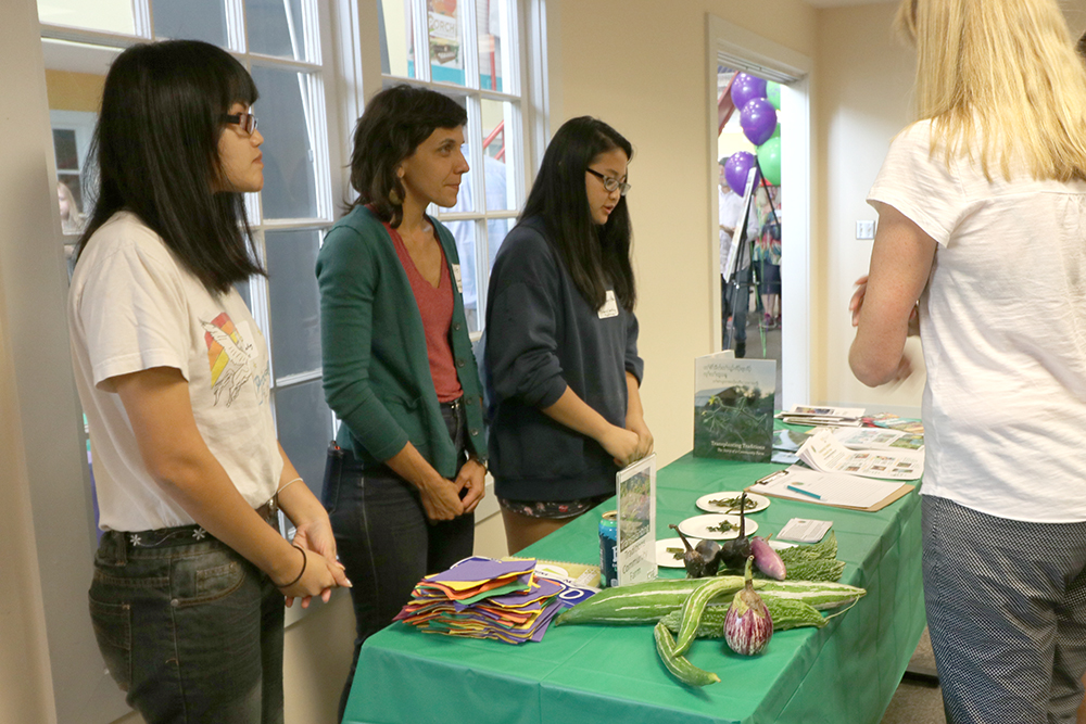 Three women behind a table with some vegetables on display