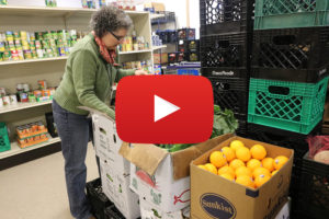 woman sorting boxes of produce, with video icon