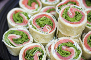 Spiral-looking slices of a wrap with lettuce, cream cheese and smoked salmon