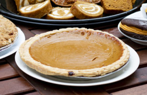 pumpkin pie on a table with the edges of other dishes nearby