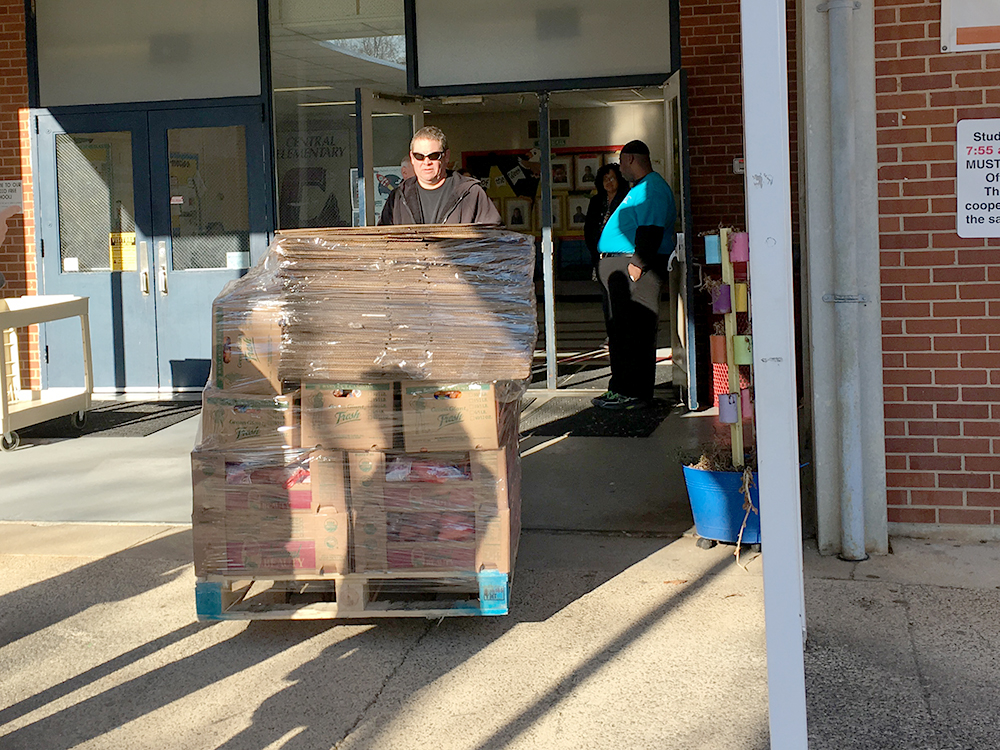 Errol pulls a pallet of food into a school