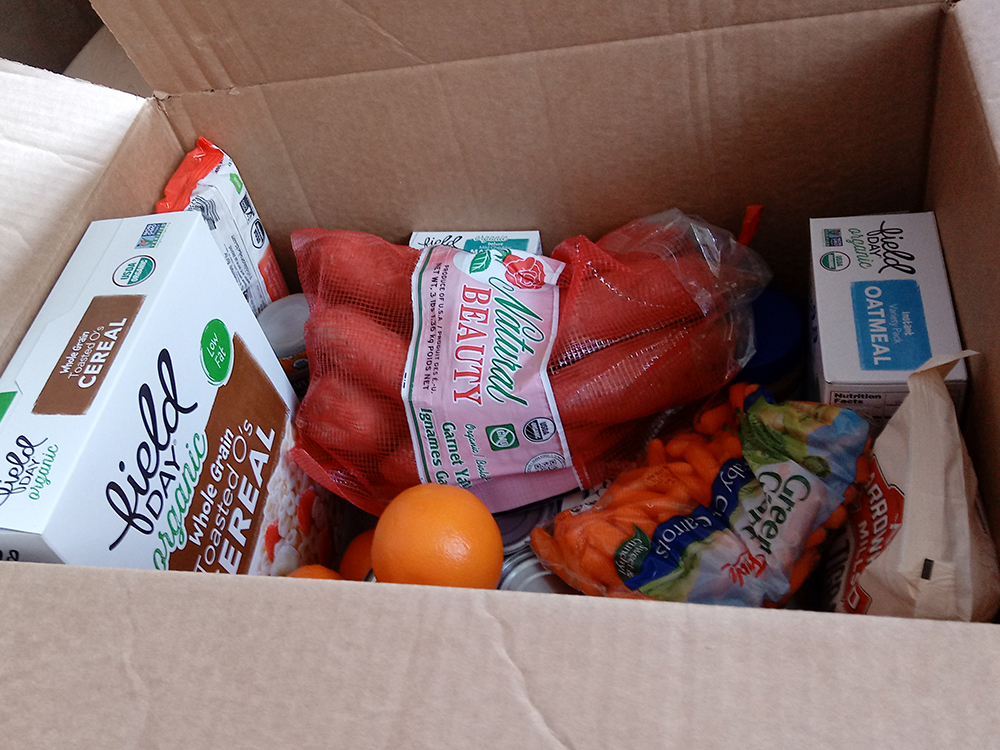 a box of food showing cereal, carrots, oranges and more