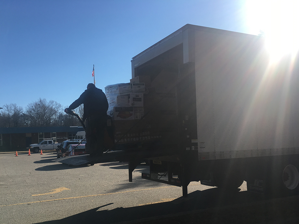 Errol unloads a pallet from the truck in the sunshine
