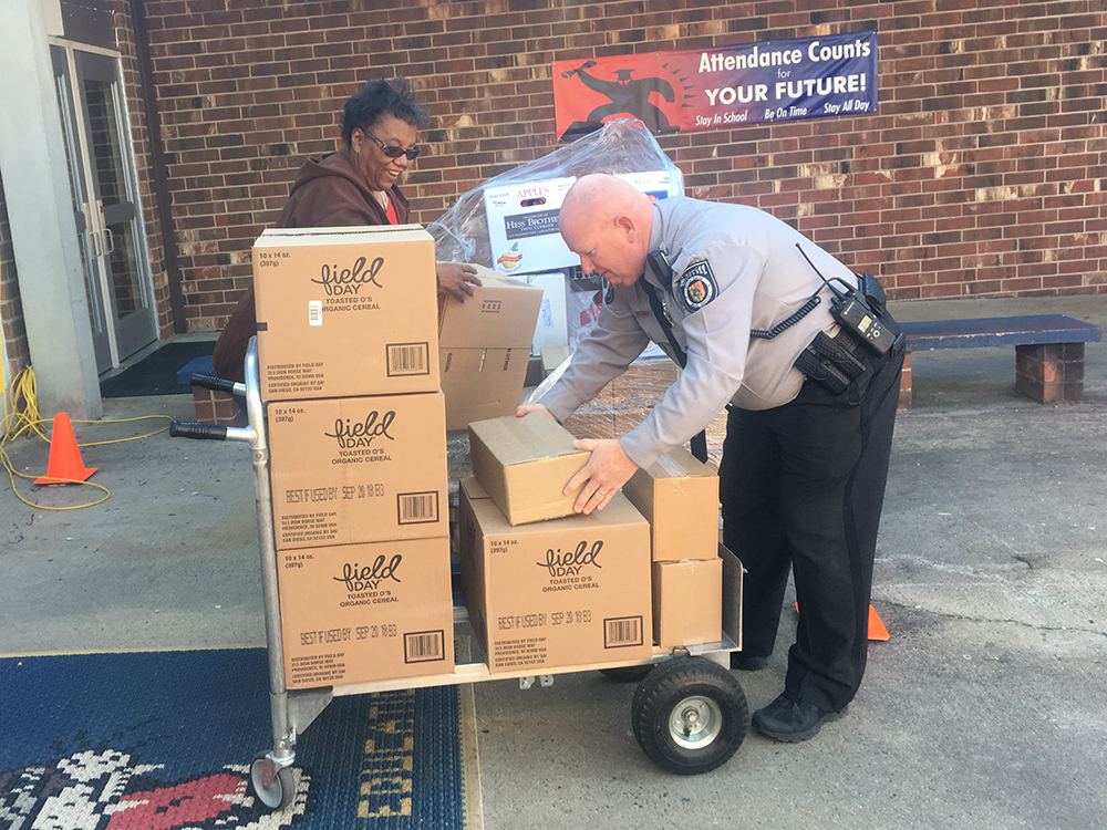 a woman and a policeman help unload food