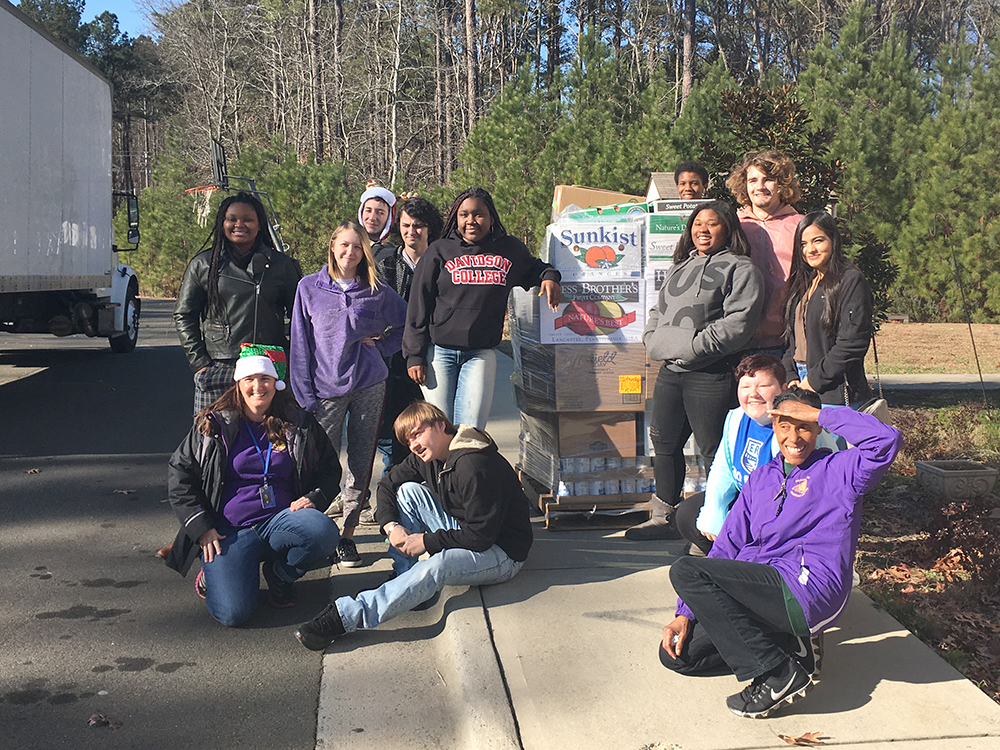a group of kids pose with a pallet of food