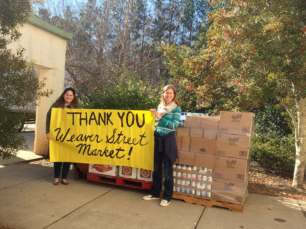 two women hold a thank you banner