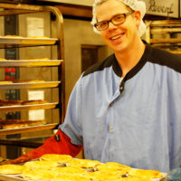 Glenn holding tray of pot pies by oven