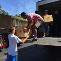 man handing another man box off the back of a truck