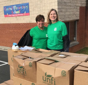 two women in PORCh shirts standing by boxes