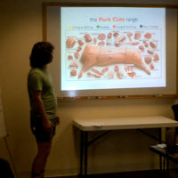 Sam looks at an image of the cuts of a hog on a screen