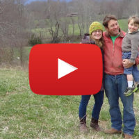 a couple with a small child standing in a field, with a video icon