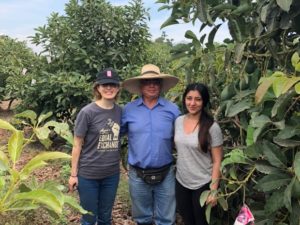 two women pose with a male farmer in a hat