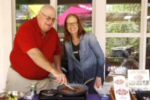 man and women fry sausage in pan