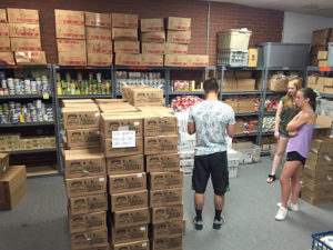 group of volunteers talking among stacks of food