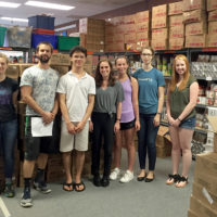 group of volunteers posing among stacks of food