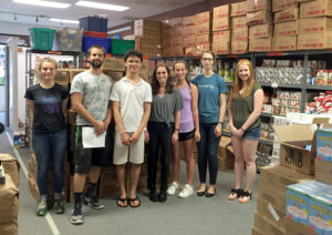 group of volunteers posing among stacks of food