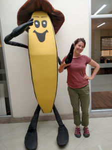 Carolyn with a model of a banana, with arms and legs and a face