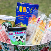 a tub of ice filled with pops and ice cream containers