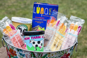 a tub of ice filled with pops and ice cream containers