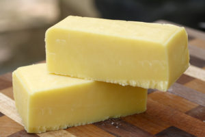 blocks of cheddar cheese on a wooden cutting board