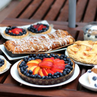 peach tart, pie, coffeecake, and shortcakes on wooden slats of table