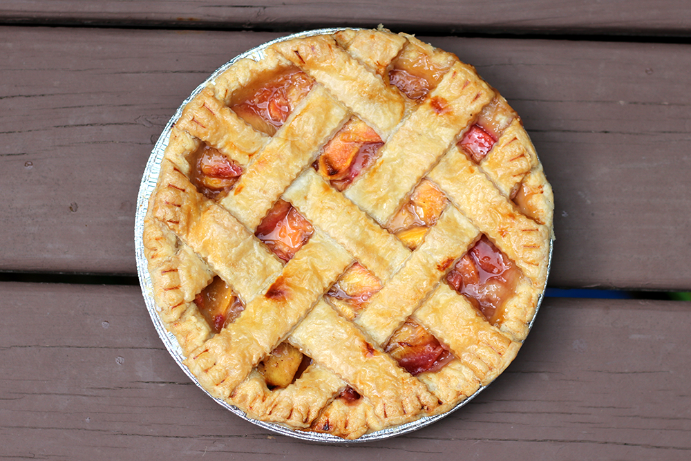 whole peach pie seen from above, on wooden deck