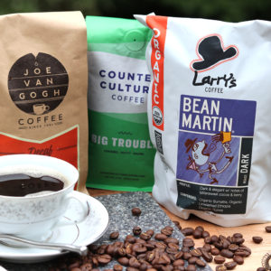 packages of coffee of various brands with coffee beans and a cup of coffee