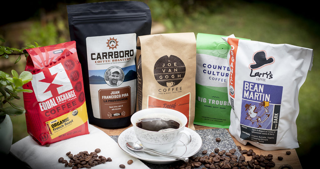 packages of coffee of various brands with coffee beans and a cup of coffee