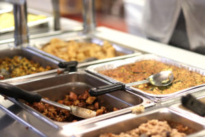 the hot bar with pans of food and serving spoons