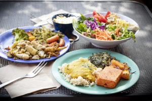 two plates of food from the hot bar, a salad, and a bowl of macaroni and cheese