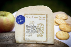 a wedge of cheese, wrapped with a label from Goat Lady dairy