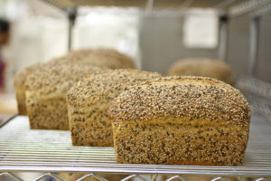 loaves of grainy bread on metal bakery shelves
