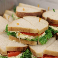 egg salad sandwiches with tomato and lettuce on a tray
