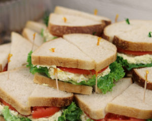 egg salad sandwiches with tomato and lettuce on a tray