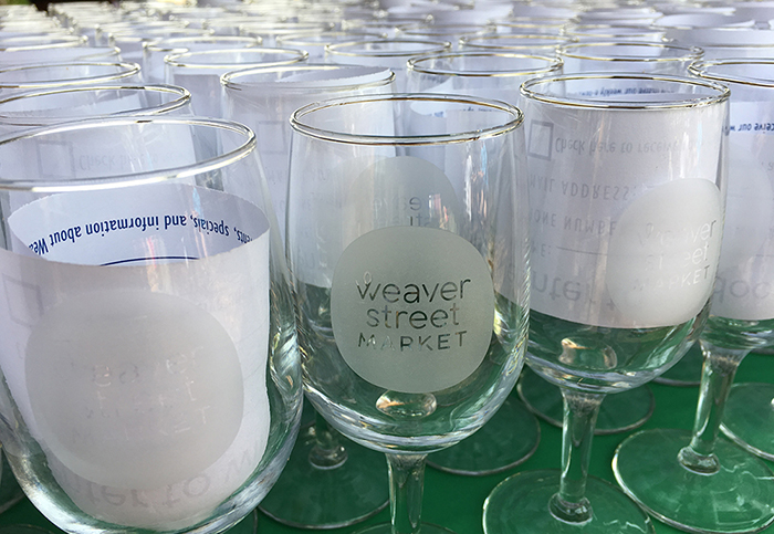 wine glasses etched with the Weaver Street logo on a table