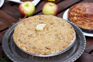 a pie with a streusel topping, posed with apples
