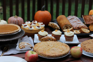 a table covered with apple and pumpkin pastries, decorated with pumpkins and apples