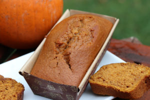 a loaf of pumpkin bread in a pan with a slice next to it