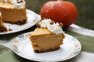 a slice of pumpkin cheesecake with whipped cream and nuts on top