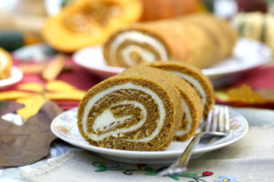 slices of pumpkin roll cake, with a curl of cake and frosting forming a spiral