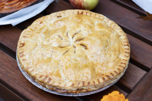 pie with top crust on table with apples and leaves