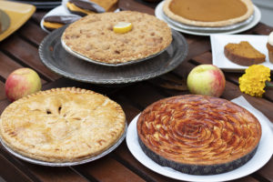 two appl epies and a tart on a table with apples