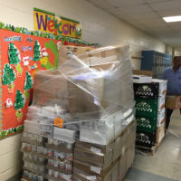boxes of food wrapped in plastic, on a pallet, in a school hallway